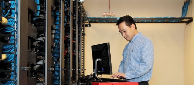 Asian man working on computer in server room